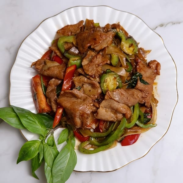 Thai Chili's spicy basil beef with bell peppers, onions, and fresh basil on a white plate.